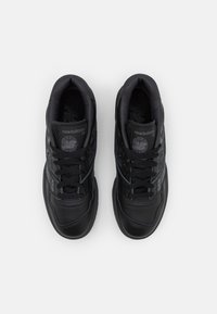 Fekete sportcipők bőr és hálós felsőrésszel, lekerekített orral, fűzővel és strukturált talppal. New Balance logó minden cipőn.