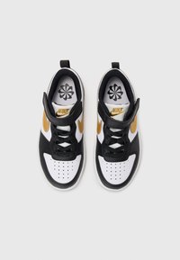 Crno-bijeli tenisice od kože i mrežastog materijala. Imaju zlatni Nike logo, perforirani vrh i crne vezice. Dizajn ravnog potplata.