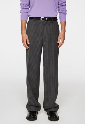 Grau gemusterte Hose mit lockerer Passform, die ein dezentes Karodesign aufweist, abgerundet mit einem schwarzen Gürtel und glänzenden schwarzen Schuhen.