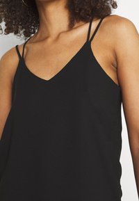 Black camisole top with a V-neckline, thin adjustable straps, and a smooth fabric texture. Simple design with no patterns or embellishments.