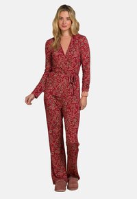 Rotes Blumen-Pyjama-Set mit langen Ärmeln und einem Wickeldesign, versehen mit einem Bindegürtel. Weicher Stoff und weit geschnittene Hosenbeine. Kombiniert mit gemütlichen Hausschuhen.