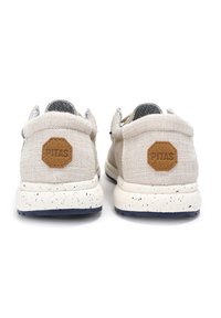 Light beige fabric shoes with textured uppers, a brown hexagonal logo, and speckled white soles with a blue accent.
