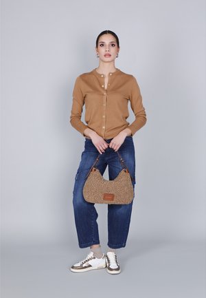 Cardigan cammello con bottoni, jeans cargo blu, borsa a tracolla beige pelosa e sneakers bianche con dettagli marroni. Outfit semplice e casual.