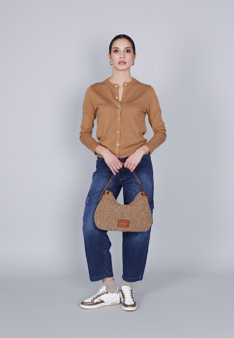 Camel cardigan med knapper, blå cargo jeans, fuzzy beige skuldertaske og hvide sneakers med brune detaljer. Enkel, afslappet outfit.