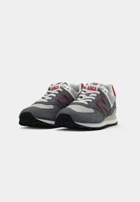 Grå ruskinds- og mesh-sneakers med røde accenter, hvide snører og sort gummisål. Har en polstret krave og broderet branding.