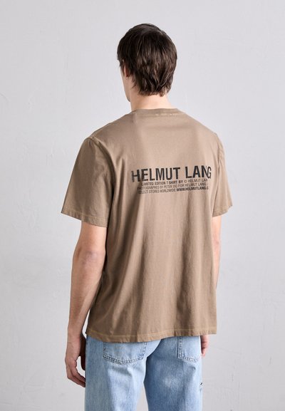 Pruun puuvillane T-särk lühikeste varrukatega. Seljal on julge must tekst, sealhulgas "HELMUT LANG" ja lisainformatsioon. Sirge alläär, millel on minimaalne tekstuur.