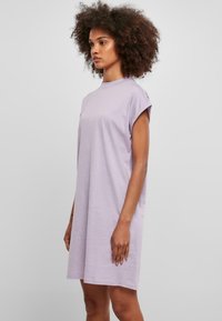 Robe lavande à manches courtes en tissu doux, avec un col rond et une coupe décontractée, s'étendant jusqu'à mi-cuisse.