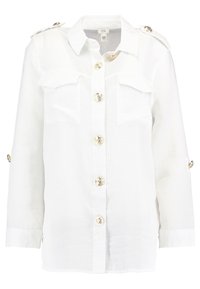 Camisa de lino blanca con un frente de botones, dos bolsillos en el pecho, botones dorados de gran tamaño y mangas cortas arremangadas con detalles de botones.