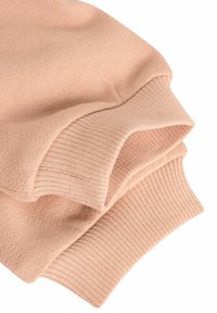 Rosa stickad tröja med ribbade manschetter, som visar en mjuk textur och en vikbar design. Materialet verkar lätt och andningsbart.