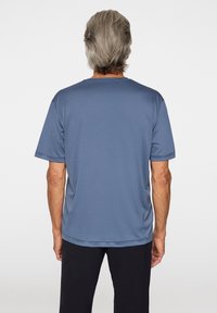 Blå kortärmad t-shirt, tillverkad av ett mjukt tyg. Har rundad nacke och en avslappnad passform, visad från baksidan.