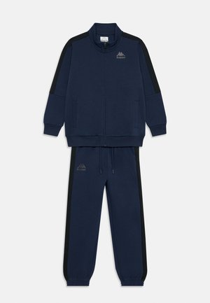 Survêtement bleu marine en tissu doux ; comprend une veste zippée avec des accents noirs sur les côtés et un pantalon assorti avec une taille élastique.