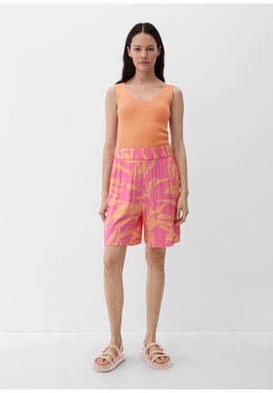 Orange gerippter Tanktop, pinke gemusterte Shorts mit abstrakten Blättern und helle Sandalen, auf einem schlichten weißen Hintergrund.