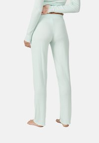 Muntgroene geribde loungebroeken, aansluitend op de taille, met een gestructureerde afwerking en onafgewerkte zomen, gezien vanuit de achterkant.