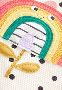 Design di tessuto colorato con un arcobaleno con un arco verde, una porta viola e uno stelo di fiore giallo su uno sfondo chiaro e texture.
