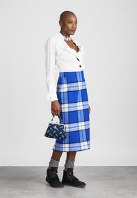 Balta pogājamā krekla, zilas rūtainas vilnas svārki, zils rokassomas, pelēkas zeķes, melni sporta apavi. Gluda auduma un izteiksmīgi raksti.