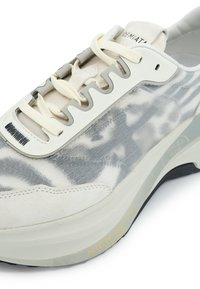 Sneaker aus creme- und graufarbenem Stoff mit einer strukturierten Oberseite, grauen Suede-Akzenten und einer weißen Gummisohle mit gelber Schrift.
