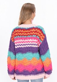 Flerfärgad stickad cardigan med livliga ränder i lila, rosa, orange, teal och gult, med en texturerad, grov garndesign.