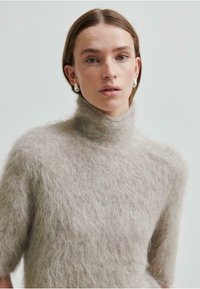 Ljust grått fluffigt polokrage med korta ärmar, tillverkat av mjukt texturerat material, med en avslappnad passform. Enkel och minimalistisk design.