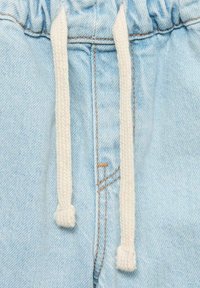 Svetlo modri denim joggerji z elastičnim pasom in kremnim zategovalcem. Opazne šivane detajle in stranske poševne žepe.