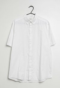 Camisa blanca de botones de manga corta con cuello, hecha de una tela ligera, con corte recto y dobladillo curvado. Incluye percha negra.