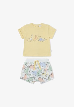 Camiseta amarilla de manga corta con tres dinosaurios de dibujos animados y pantalones cortos blancos con patrones de dinosaurios coloridos y un cordón amarillo.