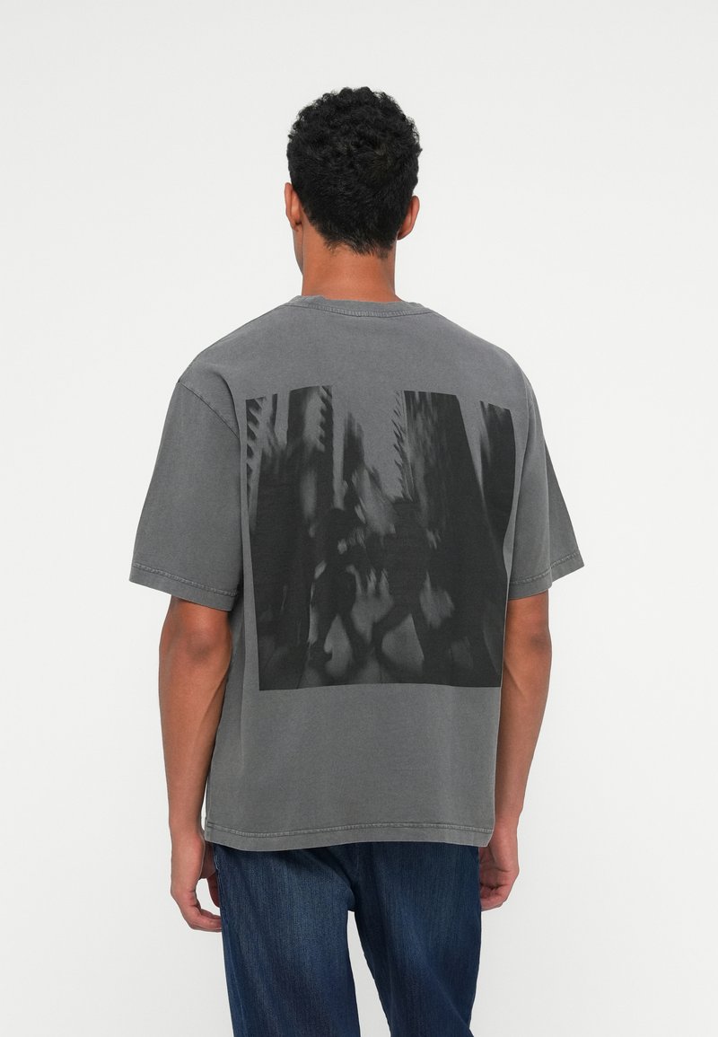 T-shirt in cotone grigio con una grande stampa grafica nera sul retro, maniche corte, colletto girocollo e vestibilità comoda.