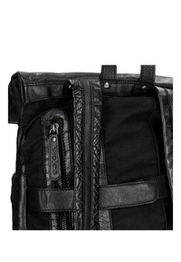 Zaino nero realizzato in materiali in pelle e tessuto, dotato di una tasca con zip, dettagli testurizzati e maniglie di trasporto doppie.