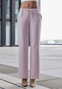 Svetloružové široké nohavice s pásom na šnúrku, hladkou textúrou a bočnými vreckami, skombinované s béžovými členkovými čižmami.