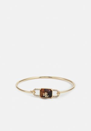 Gold bangle bracelet featuring a rectangular patterned brown stone centerpiece with a logo, accented by small clear gemstones.