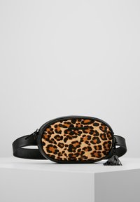 Väskan i leopardmönstrad tyg har svarta läderdetaljer, oval form, dragkedjestängning och justerbar rem. Utmärkande tofsdetalj.