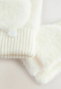 Close-up van zachte, witte breigoed met ribbels aan de manchet en knoopdetails, die gezellige texturen en pluizige stof toont.