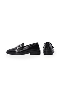Zwarte gepatineerde leren loafers met een afgeronde neus, een decoratieve zilveren gesp en een dikke zwarte rubberen zool. Gladde textuur met minimale details.