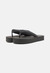 Svarta flip-flopsandaler med vadderad rem, tjock gummisula och texturerad yta. Minimalistisk design med en lätt klack och ingen synlig branding.
