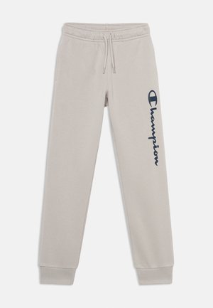 Lyse beige joggingbukser med elastisk linning og manchetter, snøre og mørkeblå lodret "Champion" logo på venstre ben.