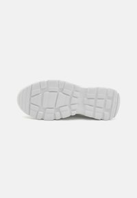 White sneaker sole with a textured, patterned design. Features deep grooves for traction and a curved heel for stability.
