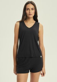 Black, sleeveless top with a V-neck and a textured ribbed pattern, paired with matching shorts. Features a small branding label on the side.