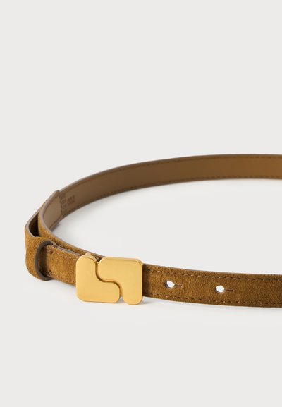 Une fine ceinture en daim beige avec une grande boucle dorée et deux trous de réglage, disposée en boucle sur fond blanc.