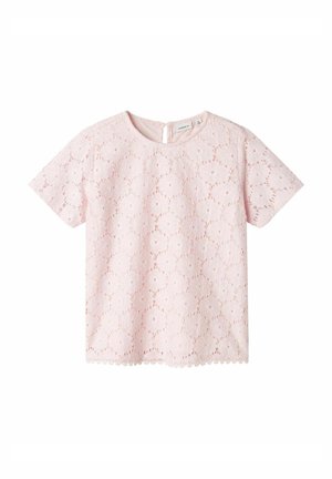Haut rose clair à manches courtes en dentelle avec des motifs floraux découpés. Il a un col rond et un ourlet festonné. Fermeture au dos avec bouton.