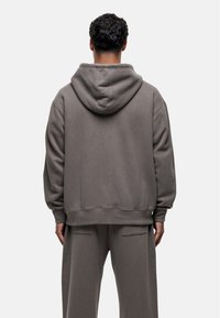 Sweatshirt met capuchon in een zachte grijze kleur, met een relaxte pasvorm, ribgebreide boorden en een buidelzak aan de voorkant. Zacht, textuurstof.