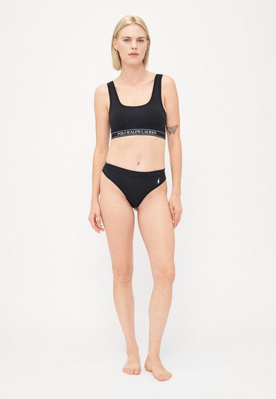 Czarny zestaw bikini wykonany z gładkiego materiału. Biustonosz ma szerokie ramiączka i elastyczną bandę z logo; dół ma niską talię z akcentem w postaci logo.