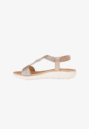 Sandalo beige piatto con cinturini intrecciati, cinturino posteriore elastico, soletta imbottita e suola bianca flessibile, visto di lato.