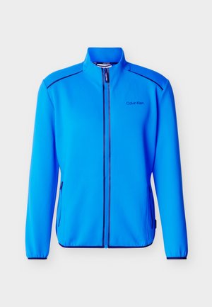 Giacca blu brillante con zip e collo alto, tasche laterali con zip, polsini elasticizzati e logo "Calvin Klein" sul lato sinistro del petto.