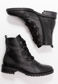 Bottines en cuir noir avec une finition texturée, dotées d'une fermeture à glissière sur le côté et de boucles décoratives avec des lacets à l'avant. Semelles en caoutchouc plates.