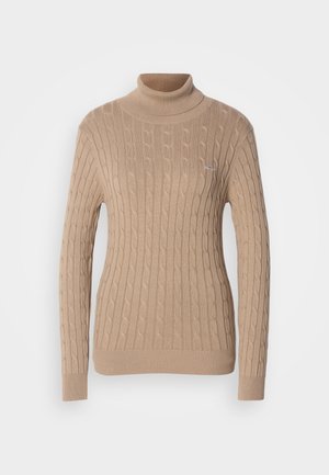 Pull en maille torsadée beige avec col roulé et poignets et ourlet côtelés. Présente un motif texturé et un petit logo sur la poitrine.