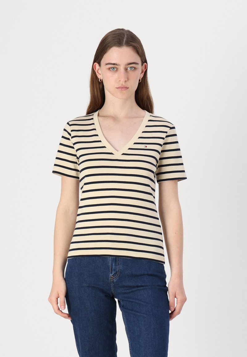Stripet kortermet t-skjorte med v-hals, laget av bomull i beige farge med marineblå striper, og en liten logo på brystet.