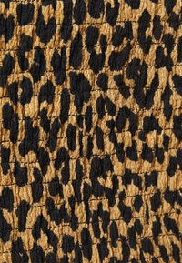 Leopardenmusterstoff mit einer strukturierten Oberfläche, der eine Mischung aus schwarzen Flecken auf goldenem Hintergrund zeigt. Er hat ein zerknittertes Erscheinungsbild.