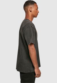 Gray, oversized cotton T-shirt with a crew neck, dropped shoulders, and raw hem. Features a faded look and subtle stitching detail.