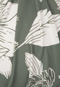 Kvetinová textília v olivovo zelenej farbe s bielymi botanickými ilustráciami, s hladkou textúrou a jemnými detailmi nariasenia.