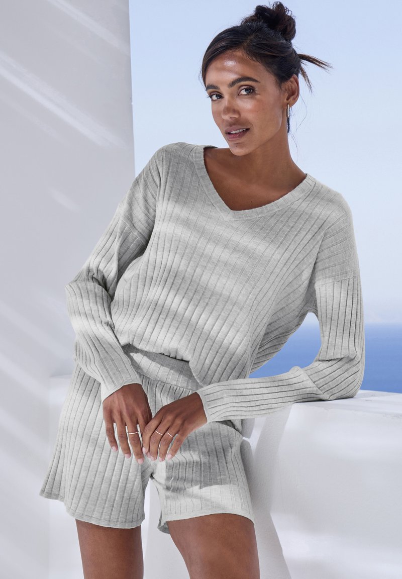 Hellgraues, geripptes Strick-Loungewear-Set mit einem V-Ausschnitt-Top und Shorts, das lange Ärmel und einen elastischen Bund aufweist, vor einem hellen Hintergrund.