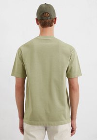 Olive green cotton t-shirt with short sleeves and a crew neck, featuring a plain design with a straight hem and minimal stitching details.